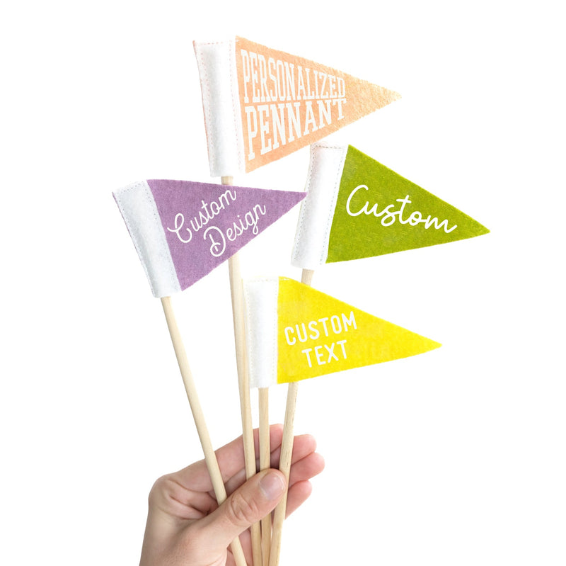 a hand holding four small pennants on sticks that say "Custom", and "Personalized"