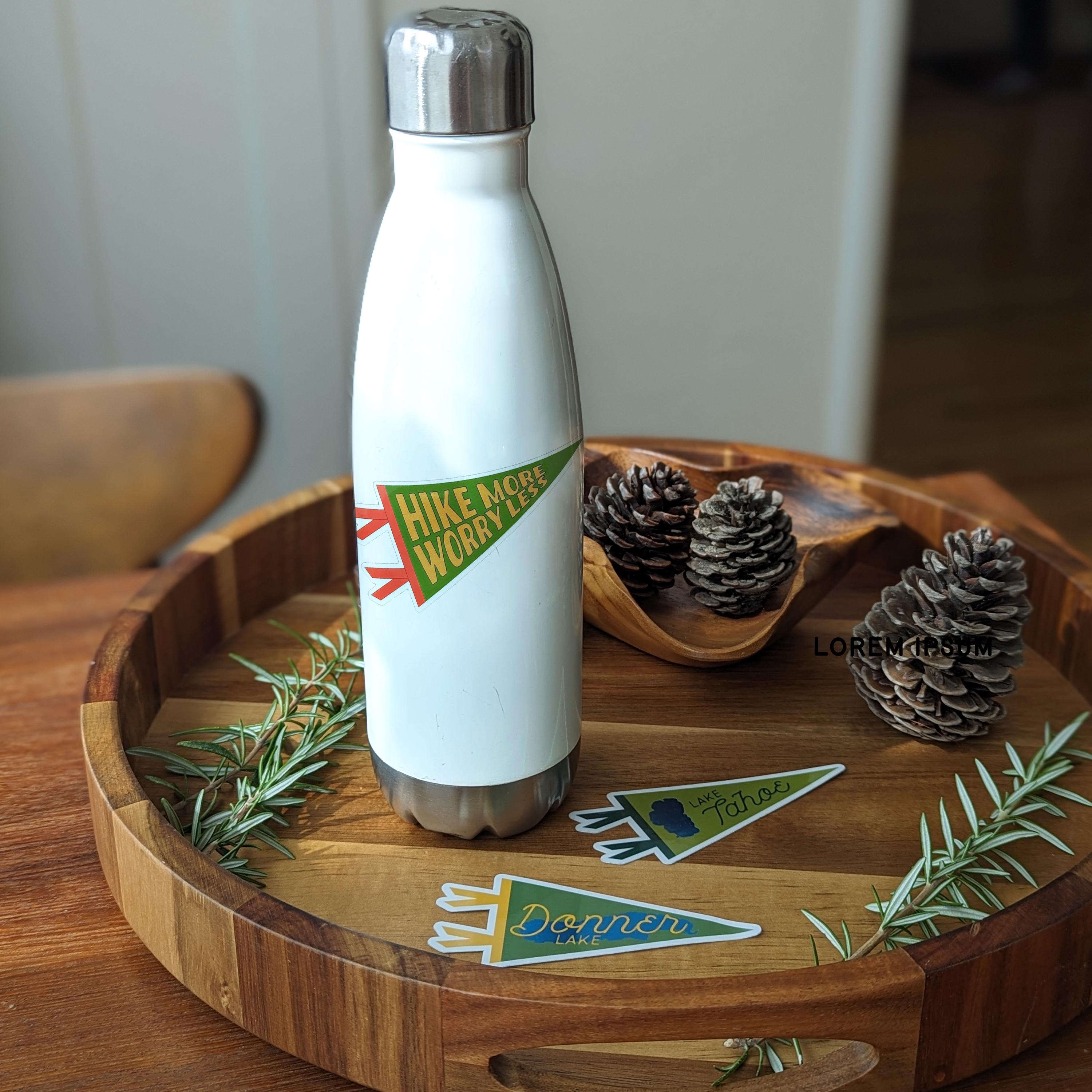 White water bottle with a green 'Hike More Worry Less'  pennant-shaped sticker