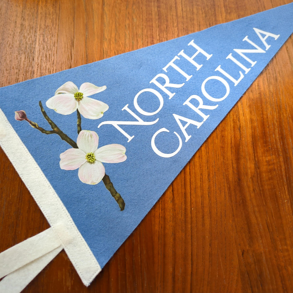 North Carolina-themed pennant with floral design on a wooden surface