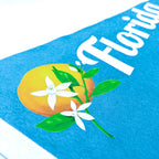 a close up photo of a turquoise pennant showing the orange blossom design