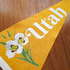 Yellow banner with white floral design and 'Utah' text displayed on a wooden surface