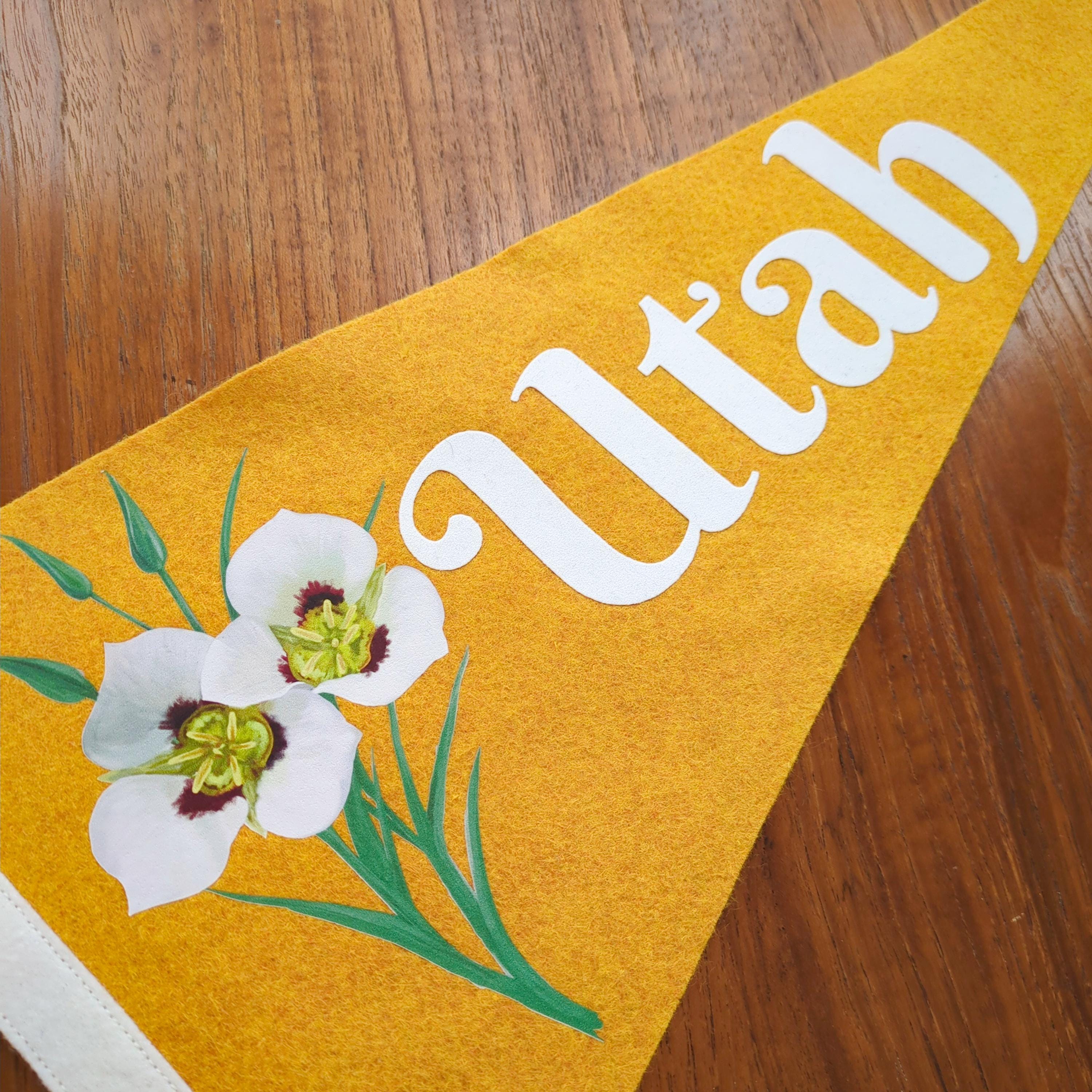 Yellow banner with white floral design and 'Utah' text displayed on a wooden surface