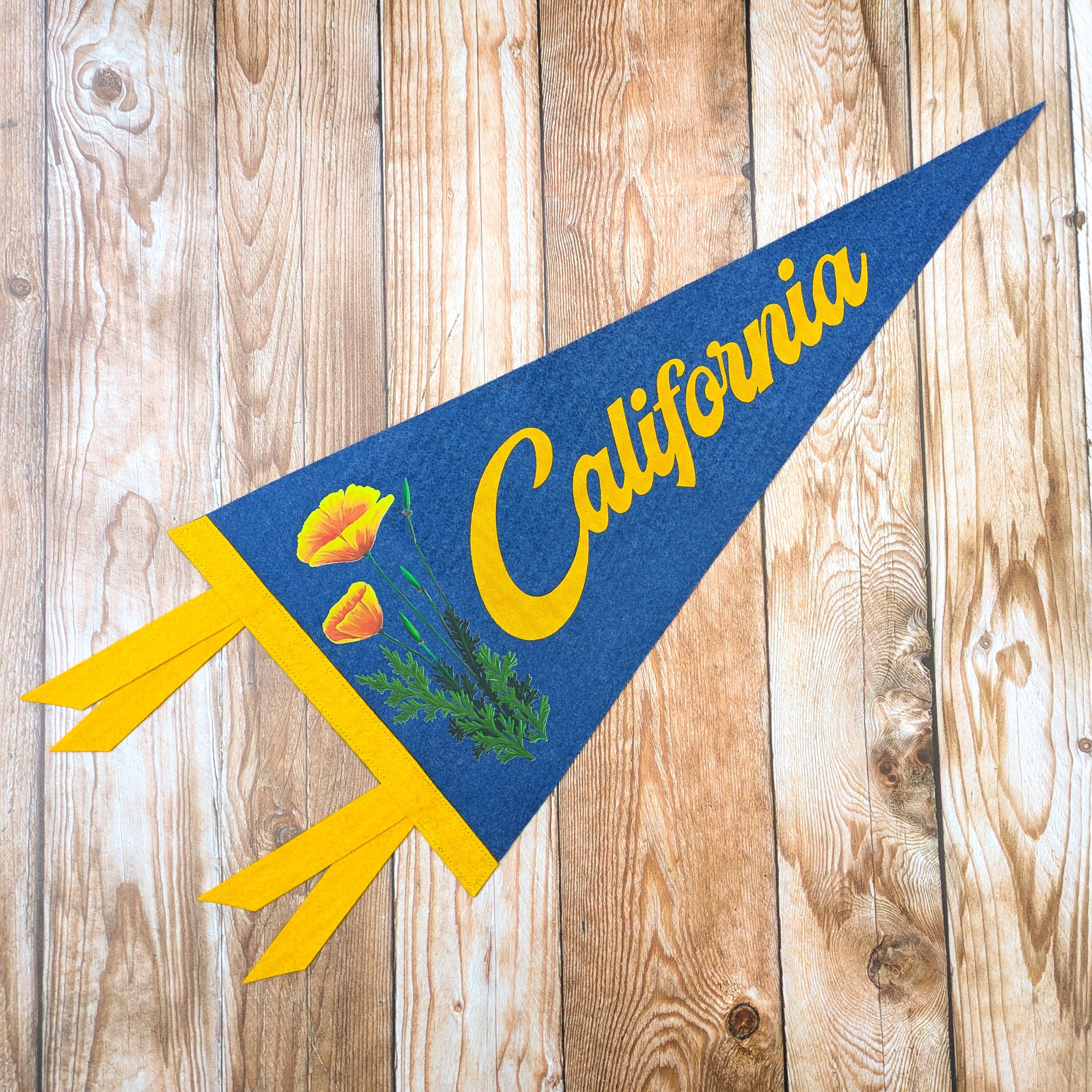 Pennant with 'California' text and a poppy graphic on a wooden background