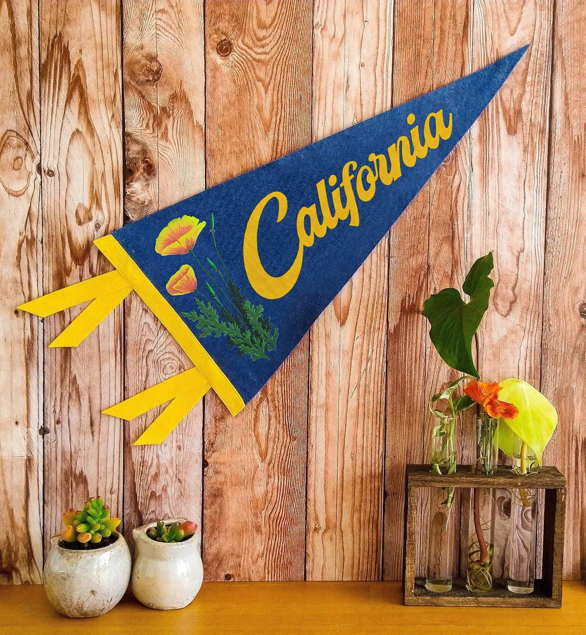 Blue and yellow 'California' pennant with a poppy design on a wooden background