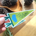 Hand holding a 'Lake Tahoe' themed pennant shaped sticker.
