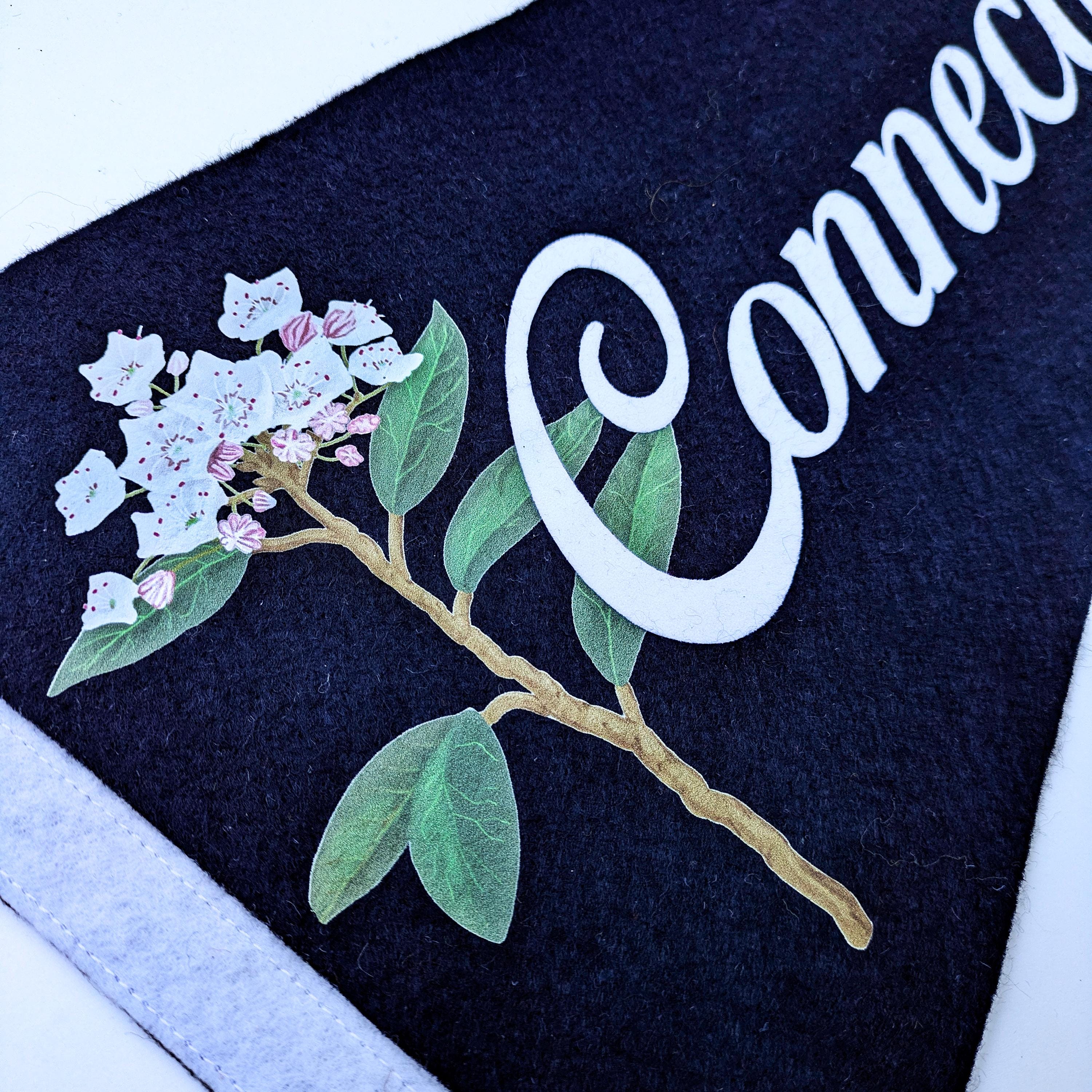 Close up of Navy Blue felt with a mountain laurel floral design and white text