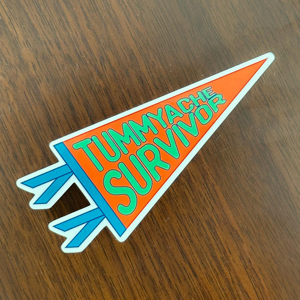 A pennant shaped sticker that says "Tummyache Survivor" in bright green bubble text on an orange background, with blue trim.