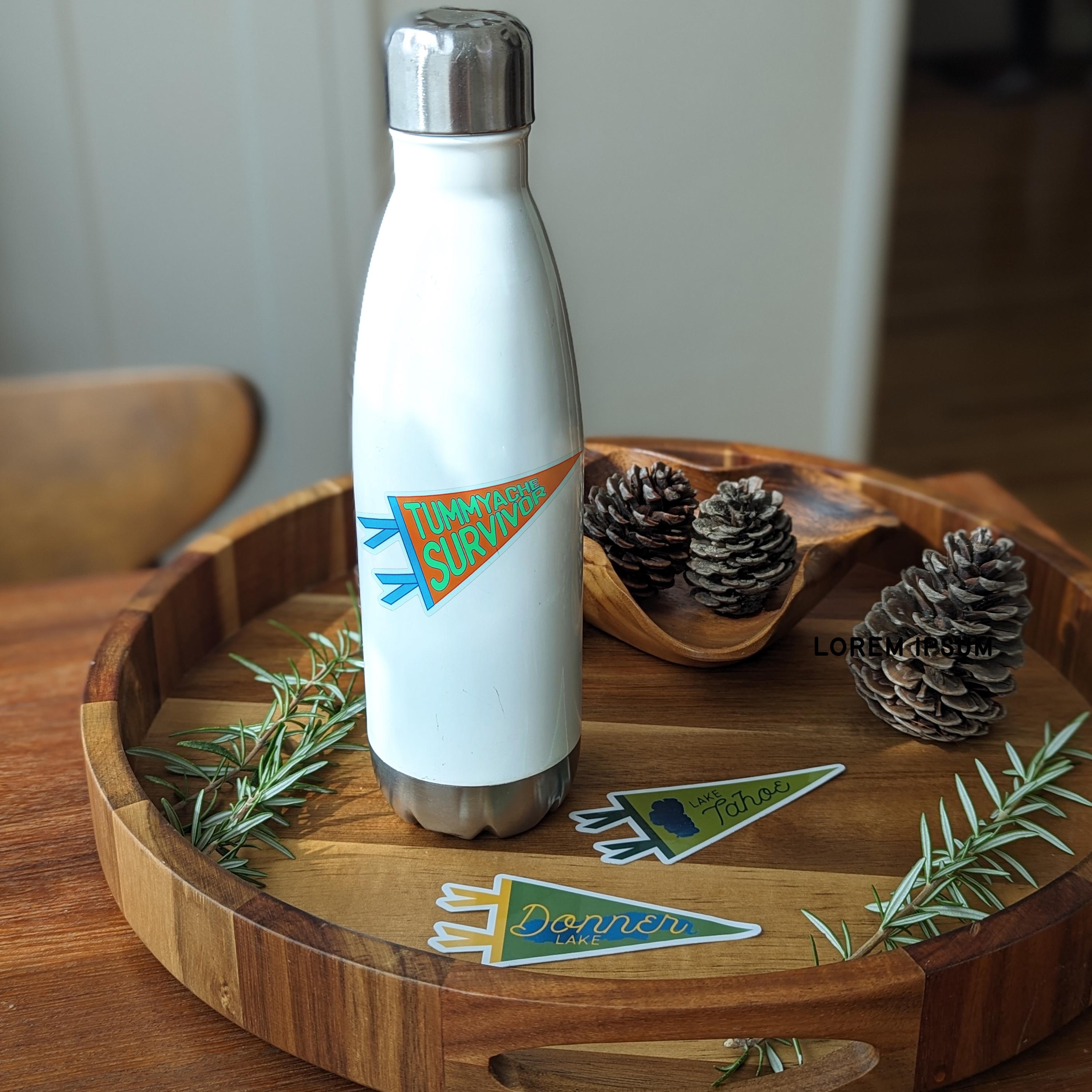 White water bottle with a 'Tummyache Survivor' pennant-shaped sticker on it