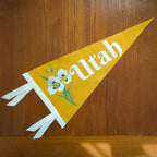 Yellow pennant with 'Utah' text and floral design on a wooden surface