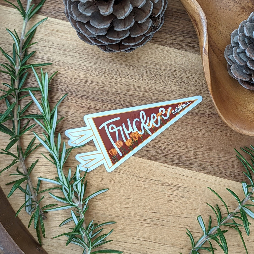 Pennant-shaped sticker with 'Truckee' text on a wooden surface with greenery