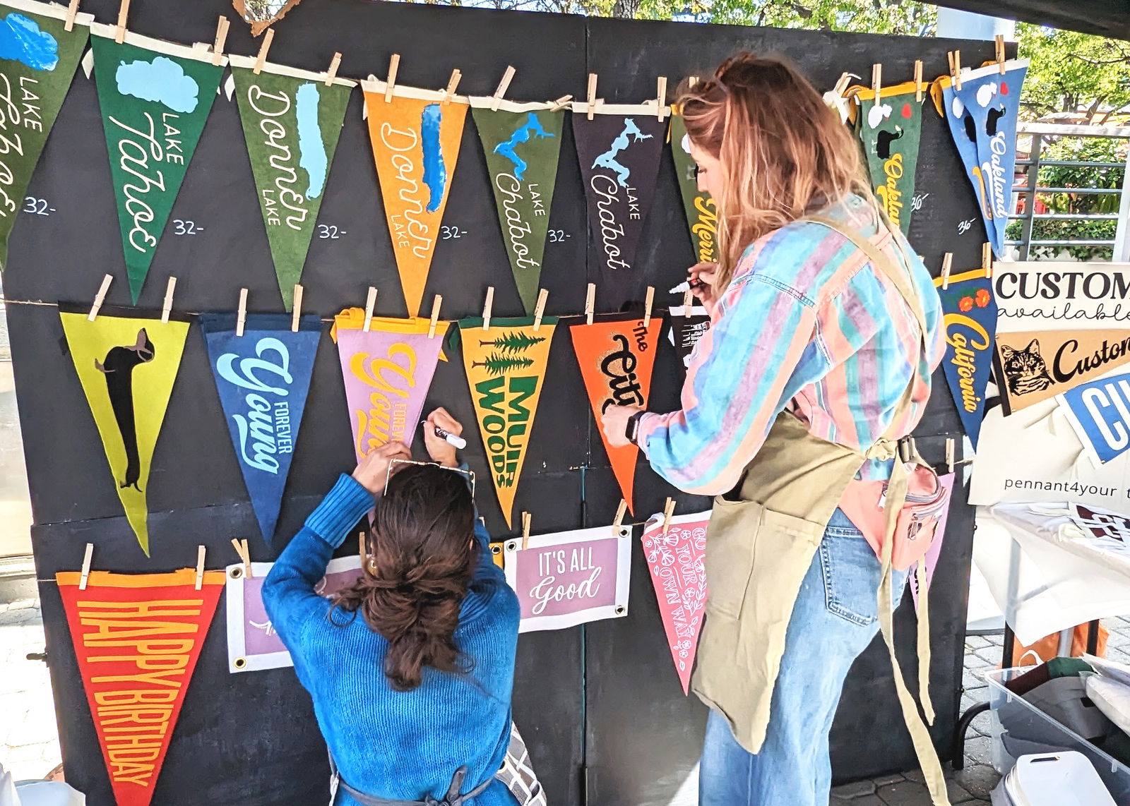 Two people interacting with colorful pennant flags on a black backdrop